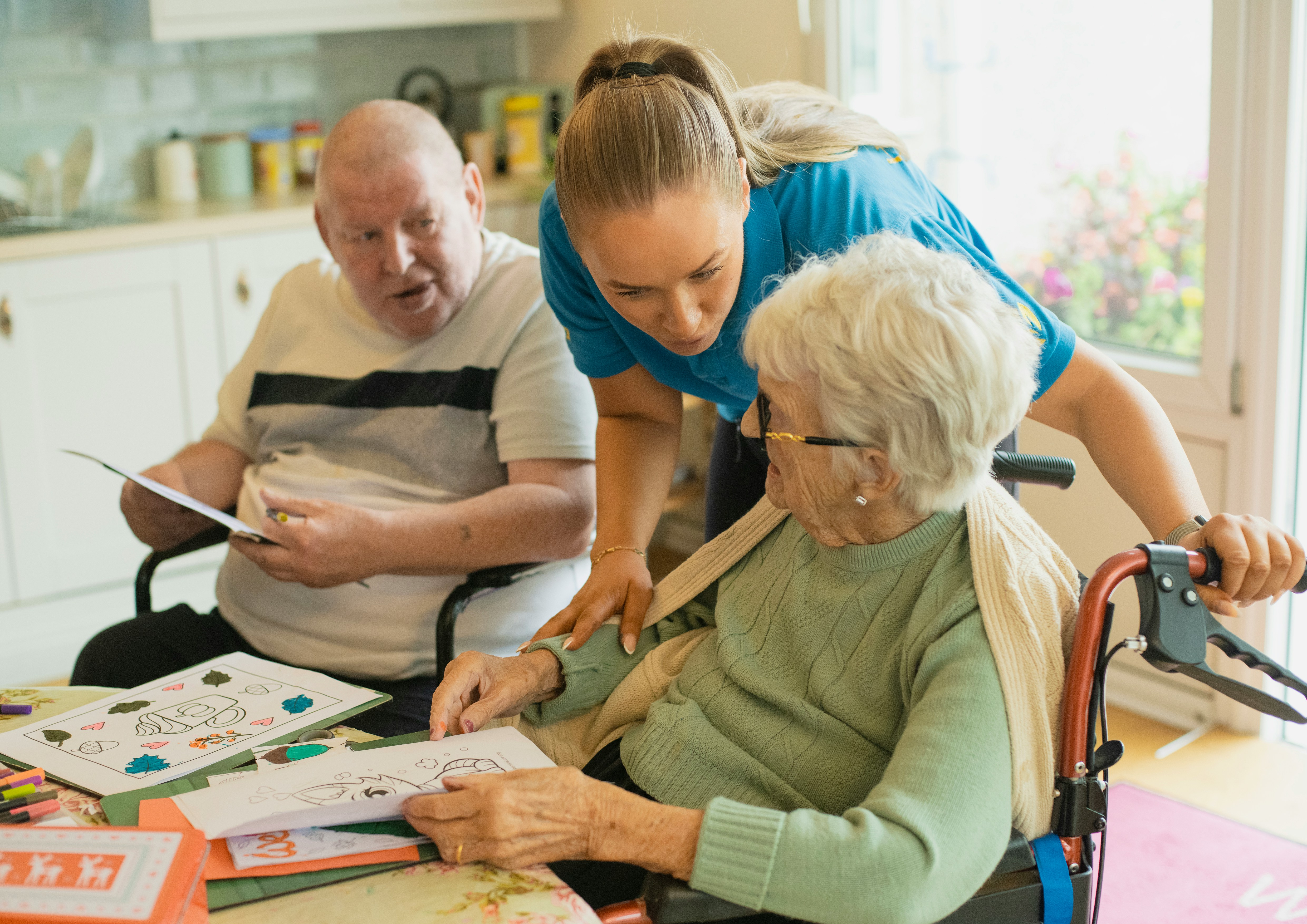 A carer supporting clients together at the kitchen table